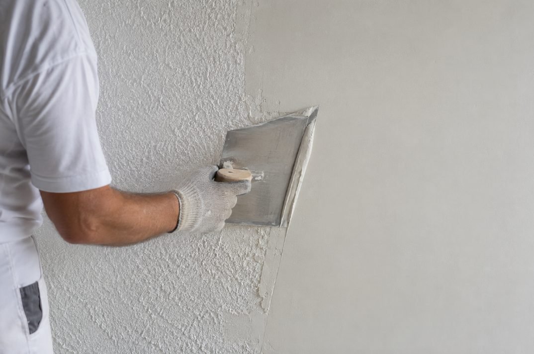 Pintor alisando con llana una pared con gotelé en Vilanova i la Geltrú